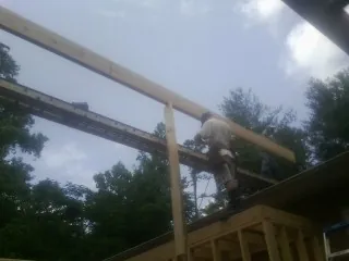 Carpenter setting a ridge beam over a new addition frame — Ice Dam Removal by Roofing Brothers in Newkirk