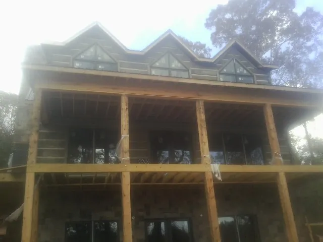 Dormers and porch framing on a large log home under construction — Roof Coating work by our crew in Newkirk