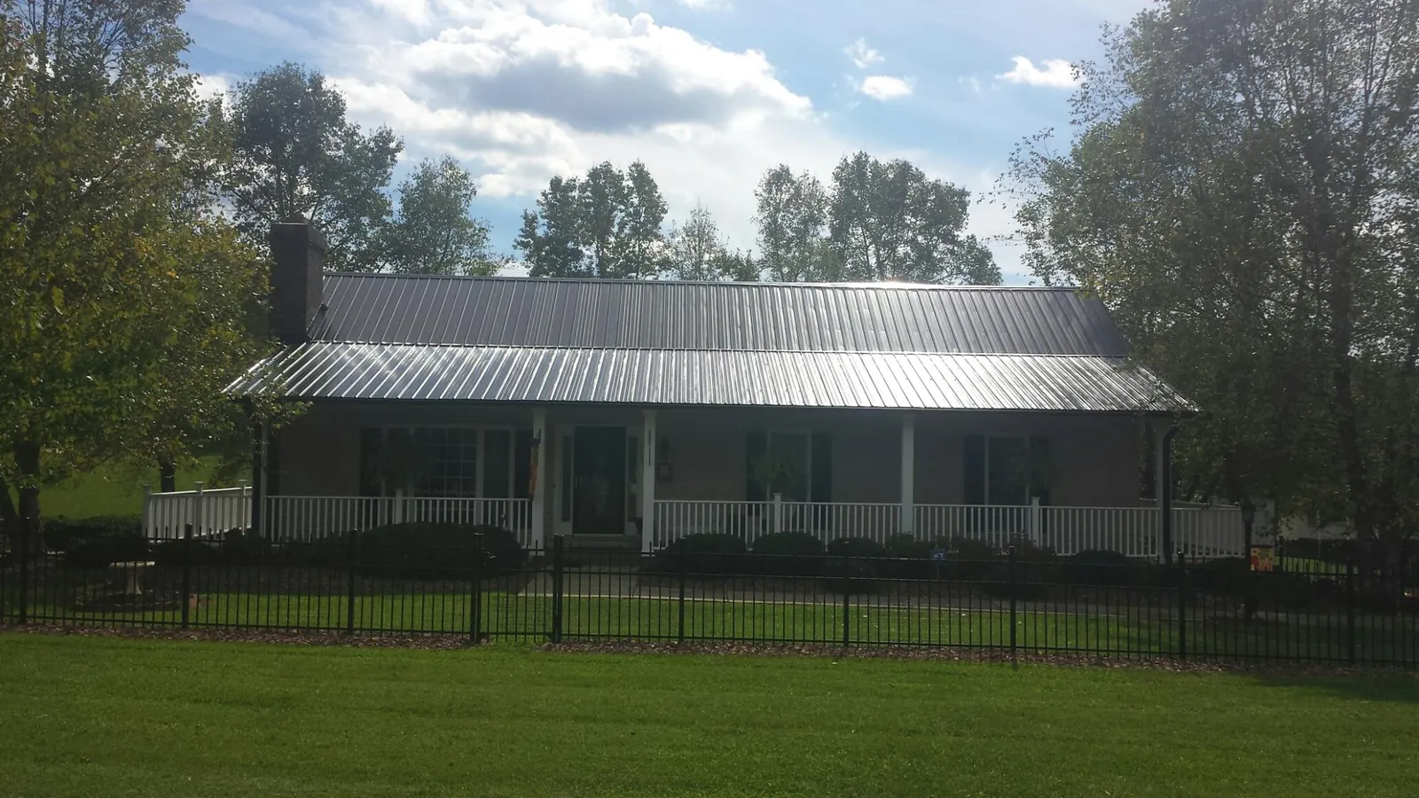 Gray metal roof on a brick ranch with a full width front porch — Gutter Guard Installation work by our crew in Newkirk