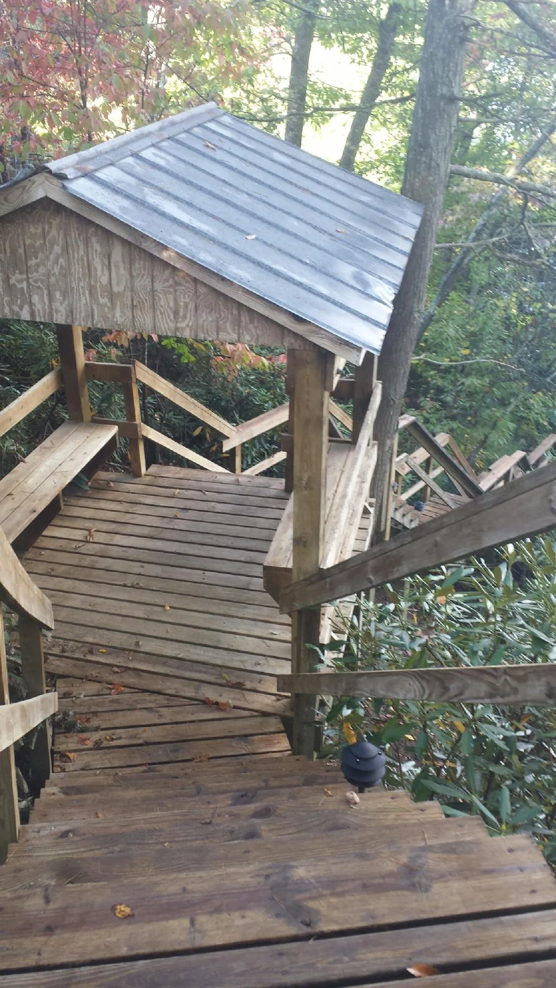 Metal roofed shelter over wooden steps on a wooded walkway — Skylight Repair & Installation work by our crew in Newkirk