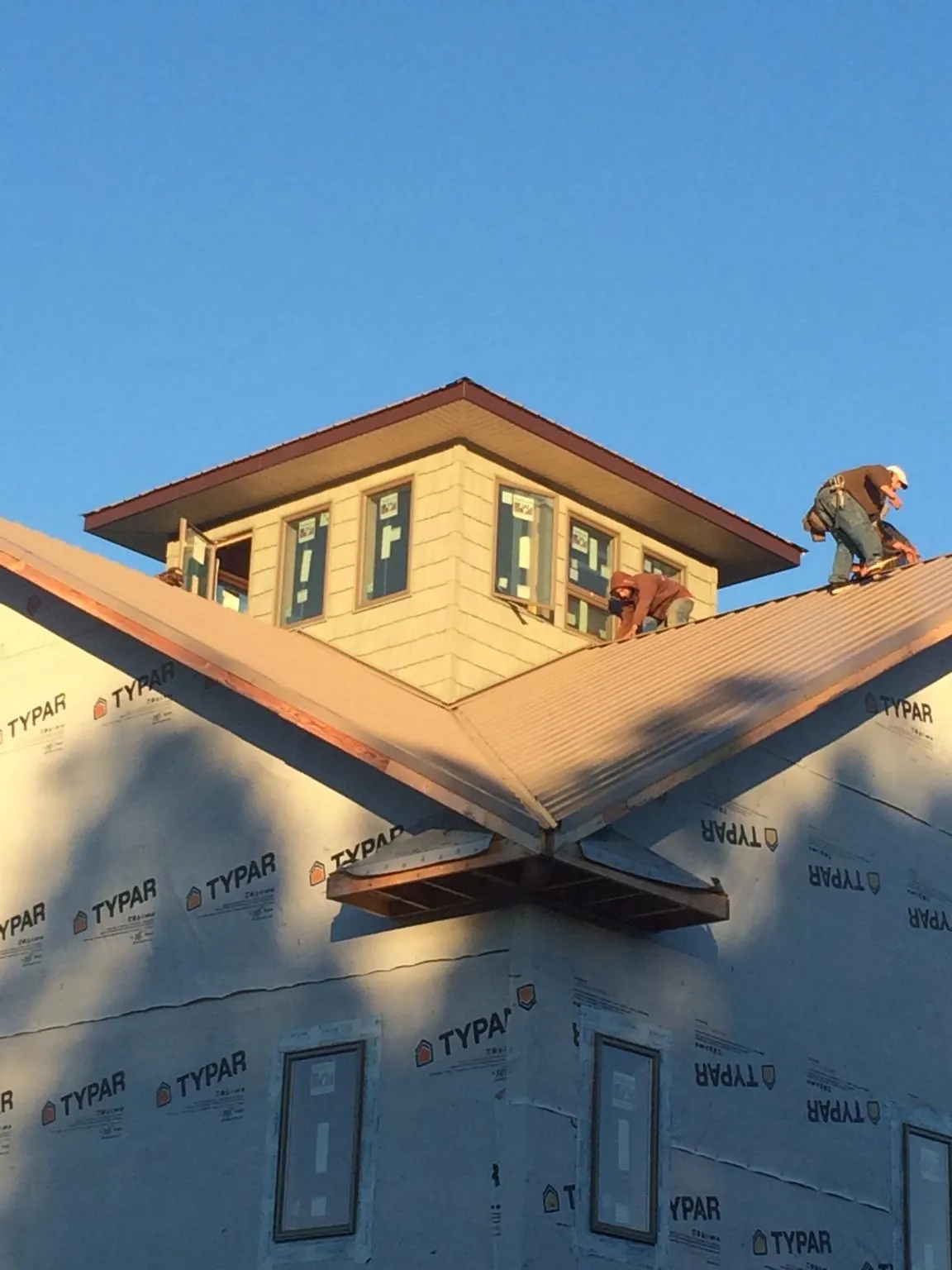 Roofers working around a rooftop cupola on a new metal roof at sunset — Roof Waterproofing in Newkirk by Roofing Brothers